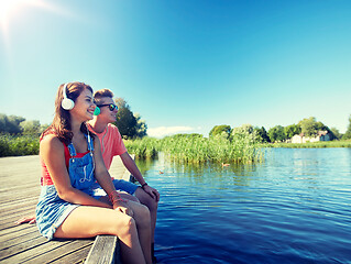 Image showing happy teenage couple with earphones on river berth