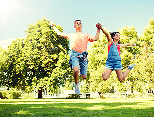 Image showing happy teenage couple jumping at summer park