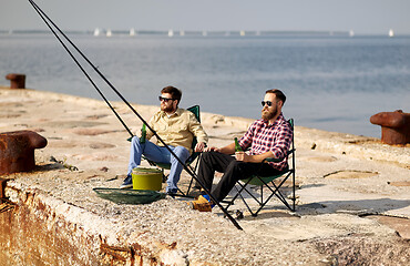 Image showing happy friends fishing and drinking beer on pier