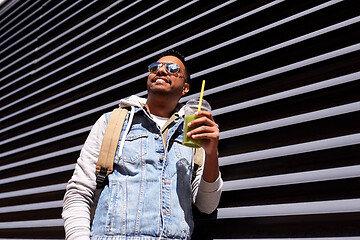 Image showing man with backpack drinking smoothie on street