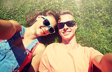 Image showing happy teenage couple taking selfie on summer grass