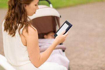 Image showing mother with stroller reading internet book at park