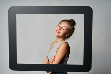 Image showing Lovely girl standing behind digital tablet frame smiling enjoying with closed eyes