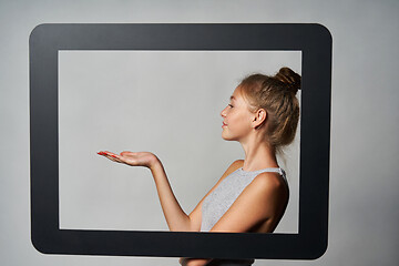 Image showing Profile of teen girl standing behind digital tablet frame and showing blank copy space on her palm