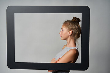 Image showing Profile of girl standing behind digital tablet frame and looking forward at blank copy space