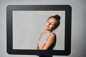 Image showing Lovely girl standing behind digital tablet frame enjoying with closed eyes