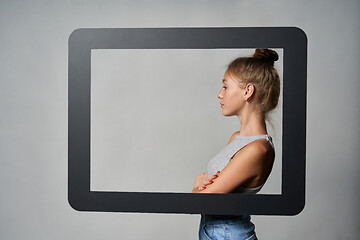 Image showing Profile of girl standing behind digital tablet frame and looking forward at blank copy space