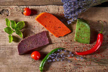 Image showing Three different cheeses on rough wooden planks: lavender, paprika and pesto cheeses