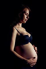 Image showing Profile of pregnant woman over black background feeling calmness with closed eyes