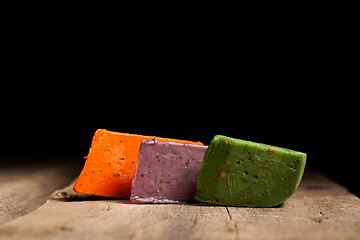 Image showing Three different gourmet cheeses on rough woode planks