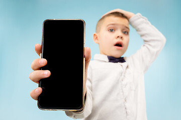 Image showing Indoor portrait of attractive young boy holding blank smartphone