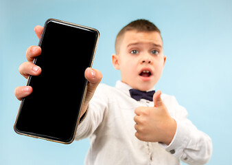 Image showing Indoor portrait of attractive young boy holding blank smartphone