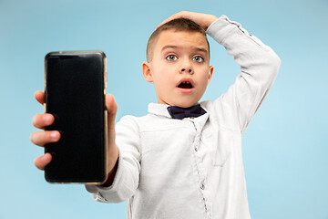 Image showing Indoor portrait of attractive young boy holding blank smartphone