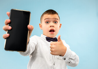 Image showing Indoor portrait of attractive young boy holding blank smartphone