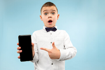 Image showing Indoor portrait of attractive young boy holding blank smartphone