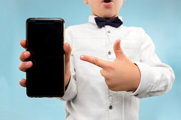 Image showing Indoor portrait of attractive young boy holding blank smartphone