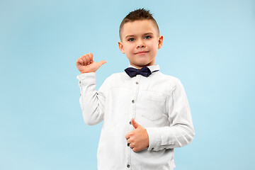 Image showing The happy teen boy standing and smiling against blue background.