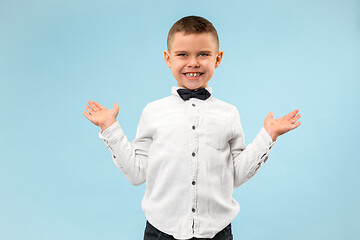 Image showing The happy teen boy standing and smiling against blue background.