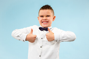 Image showing The happy teen boy standing and smiling against blue background.