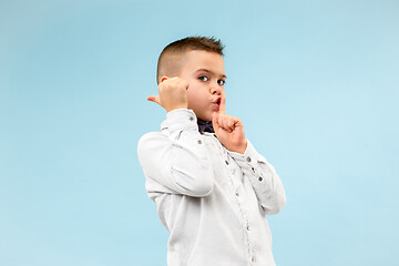 Image showing The teen boy whispering a secret behind her hand over blue background