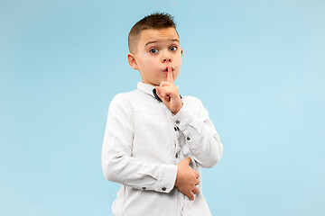 Image showing The teen boy whispering a secret behind her hand over blue background