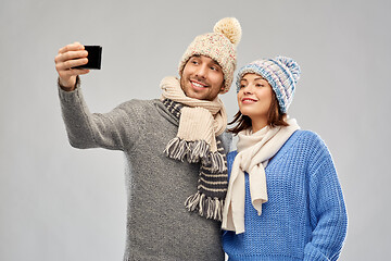 Image showing couple in winter hats taking selfie by smartphone