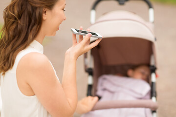 Image showing happy mother with smartphone and stroller at park