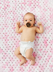 Image showing baby girl in diaper lying with pacifier on blanket