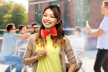 Image showing happy asian woman with bow tie over rooftop party