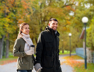 Image showing couple with tumbler walking along autumn park