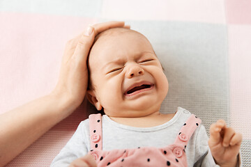 Image showing mother\'s hand touching crying little baby daughter