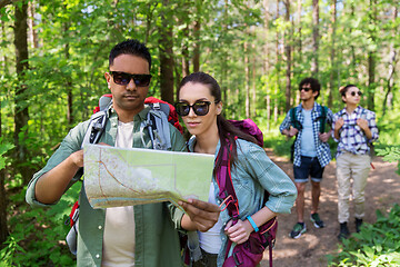 Image showing friends with map and backpacks hiking in forest