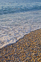 Image showing Pebble stones by the sea. Waves of blue Tyrrhenian sea.