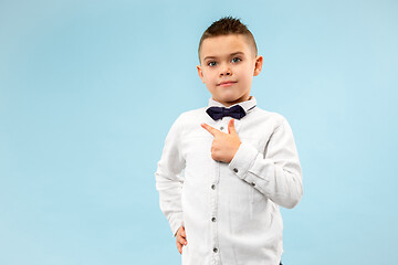 Image showing The happy teen boy standing and smiling against blue background.