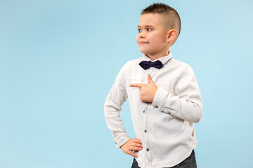 Image showing The happy teen boy standing and smiling against blue background.