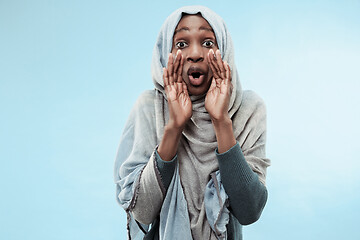 Image showing Isolated on blue young africasual woman shouting at studio