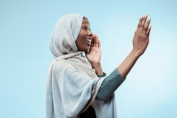 Image showing Isolated on blue young africasual woman shouting at studio