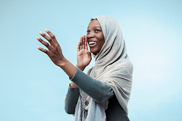 Image showing Isolated on blue young africasual woman shouting at studio