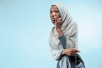 Image showing The young african woman whispering a secret behind her hand over blue background