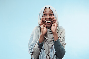 Image showing Isolated on blue young africasual woman shouting at studio