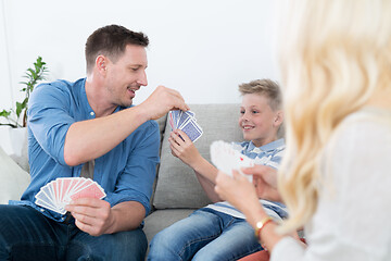 Image showing Happy young family playing card game at home.