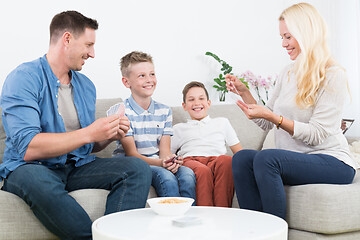 Image showing Happy young family playing card game at home.