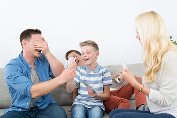 Image showing Happy young family playing card game at home.