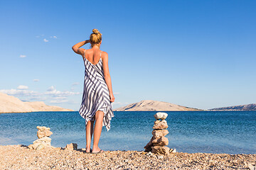 Image showing Happy carefree woman enjoying late afternoon walk on white pabbled beach on Pag island, Croatia