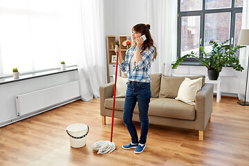 Image showing woman with cleaning home and calling on smartphone