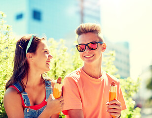 Image showing happy teenage couple eating hot dogs in city