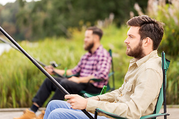 Image showing male friends with fishing rods on lake