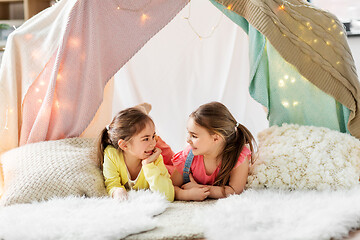 Image showing happy girls lying in kids tent and talking at home