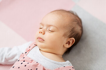 Image showing sleeping baby girl in pink suit lying on blanket