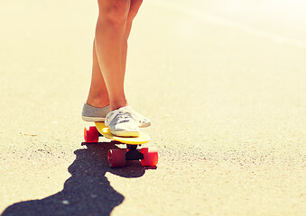 Image showing legs of young woman riding skateboard on road